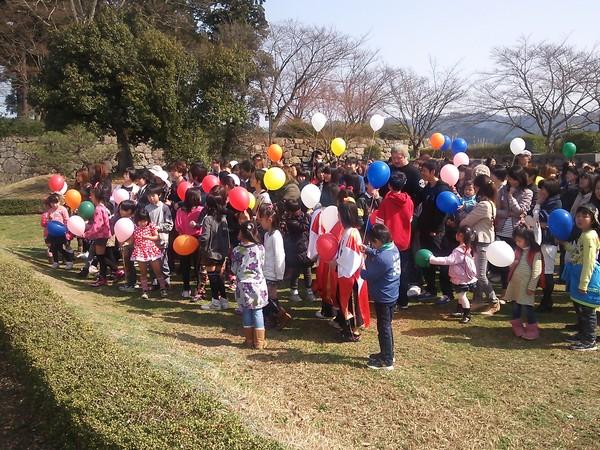 風船を持っている子供や保護者らが角谷 淳志選手を囲んで話をしている写真